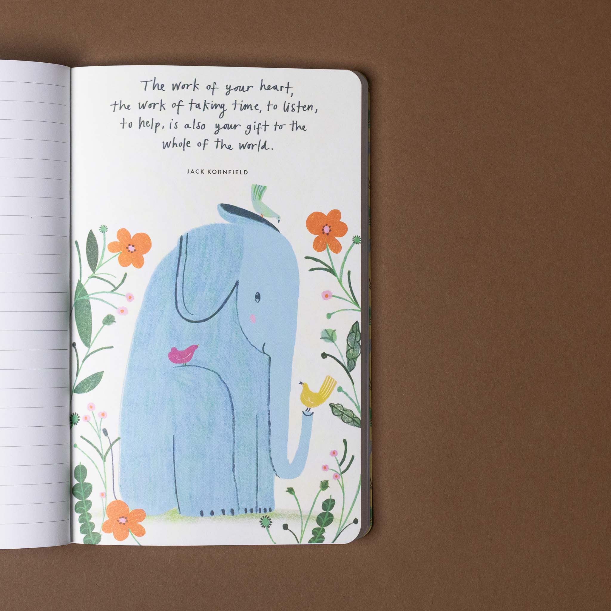 Open notebook with a blue elephant illustration and floral design on a brown background