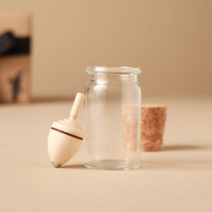 light-wood-spinning-top-next-to-glass-jar