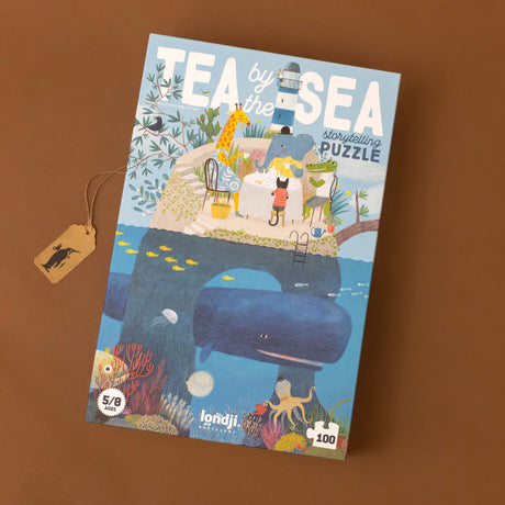Tea-by-the-Sea-100-piece-Interactive-Puzzle-box-with-a-whale-under-an-island-with-coral-beneath-the-water-and-a-tea-party-above