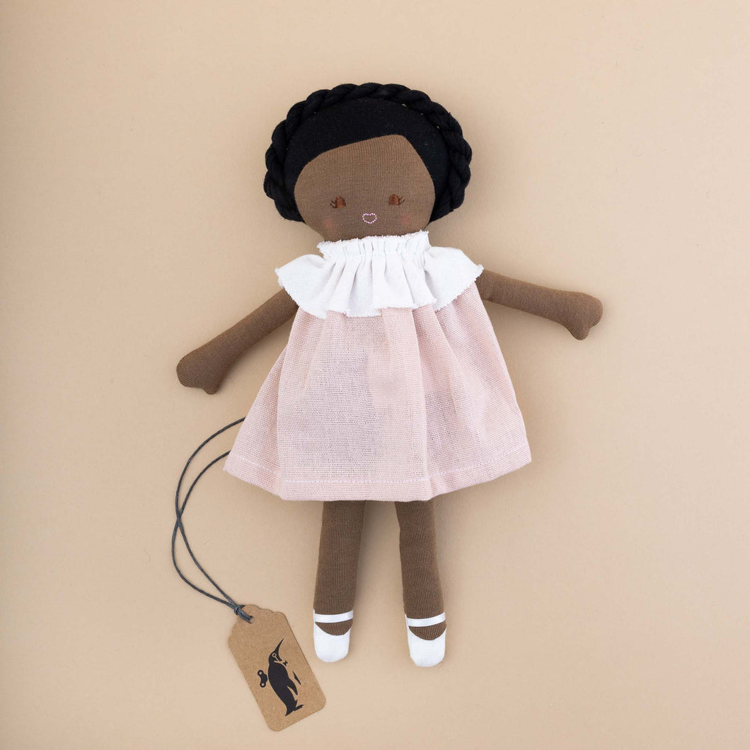 dark-skinned-doll-wearing-pink-dress-with-ruffled-collar-and-white-slippers