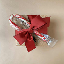 Load image into Gallery viewer, cinnamon-candy-cane-shown-tied-with-red-ribbon-on-top-of-wrapped-gift