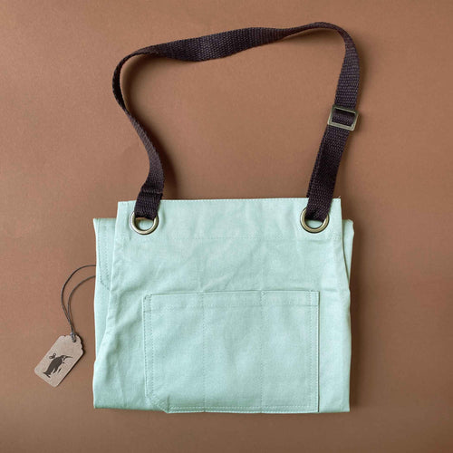 cotton-twill-apron-in-sage-color-shown-folded-with-top-pocket-showing-and-adjustable-brown-neck-loop
