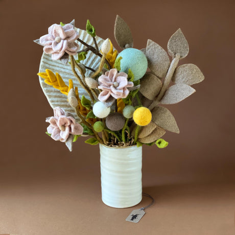 white-ceramic-vase-containing-bouquet-of-cream-palm-leaf-brown-harvest-leaf-pink-magnolia-branches-ochre-cornflower-branches-an-variety-of-pom-flowers