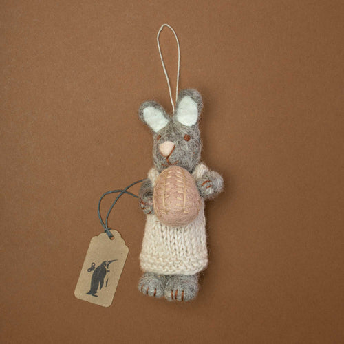 felted-grey-rabbit-with-knitted-beige-dress-holding-a-lavender-colored-egg-in-her-hands