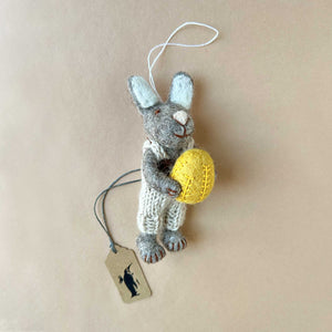 grey-felted-bunny-with-beige-knitted-overall-and-yellow-egg-in-hands