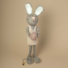 Load image into Gallery viewer, grey-felted-jumbo-sized-rabbit-with-knitted-beige-dress-holding-a-lavender-colored-and-embroidered-egg-in-her-hands