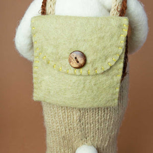 detail-of-backside-showing-a-sage-green-backpack-closed-with-a-wooden-brown-button