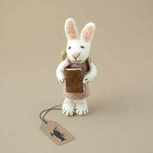 Load image into Gallery viewer, small-white-bunnz-ornament-with-knitted-lavender-colored-dress-holding-a-brown-book-iher-hands
