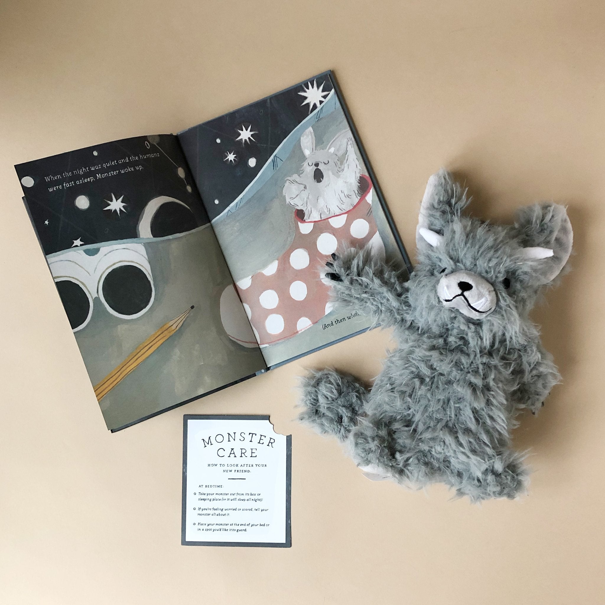 good-night-monster-grey-stuffed-animal-with-horns-and-card-detailing-monster-care-and-interior-page-of-book