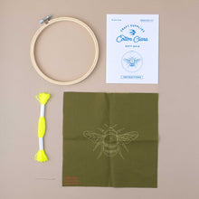 Load image into Gallery viewer, contents of the ebroidery  Bee kit showing yellow thread, a loop, the design of the bee on green cloth and the instructions booklet
