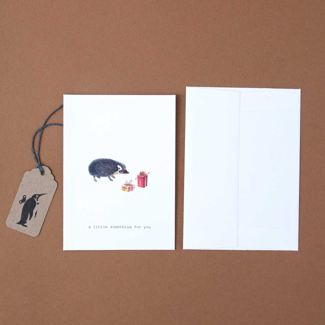 white-greeting-card-illustrated-hedgehog-with-gifts-and-black-text-reading-a-little-something-for-you
