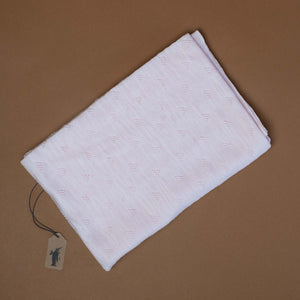 pale-pink-blanket-with-triangle-accents-in-stitching