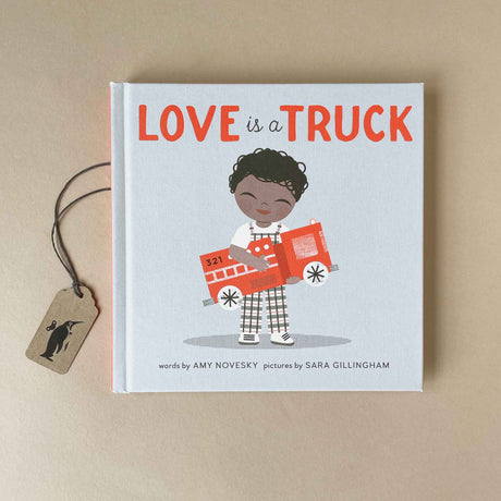 love-is-a-truck-book-cover-featuring-the-title-in-red-letters-and-a-young-child-in-checkered-overalls-holding-a-red-fire-truck