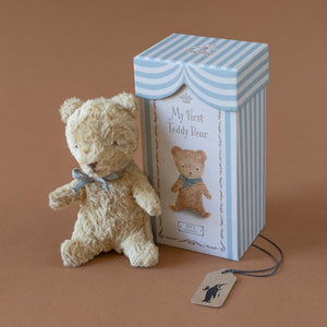 tan-bear-with-blue-bow-next-to-blue-striped-box