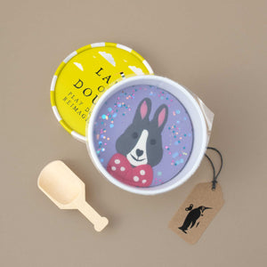 container-of-nnatural-play-dough-with-grey-bunny-image-purple-background-and-wooden-scoop