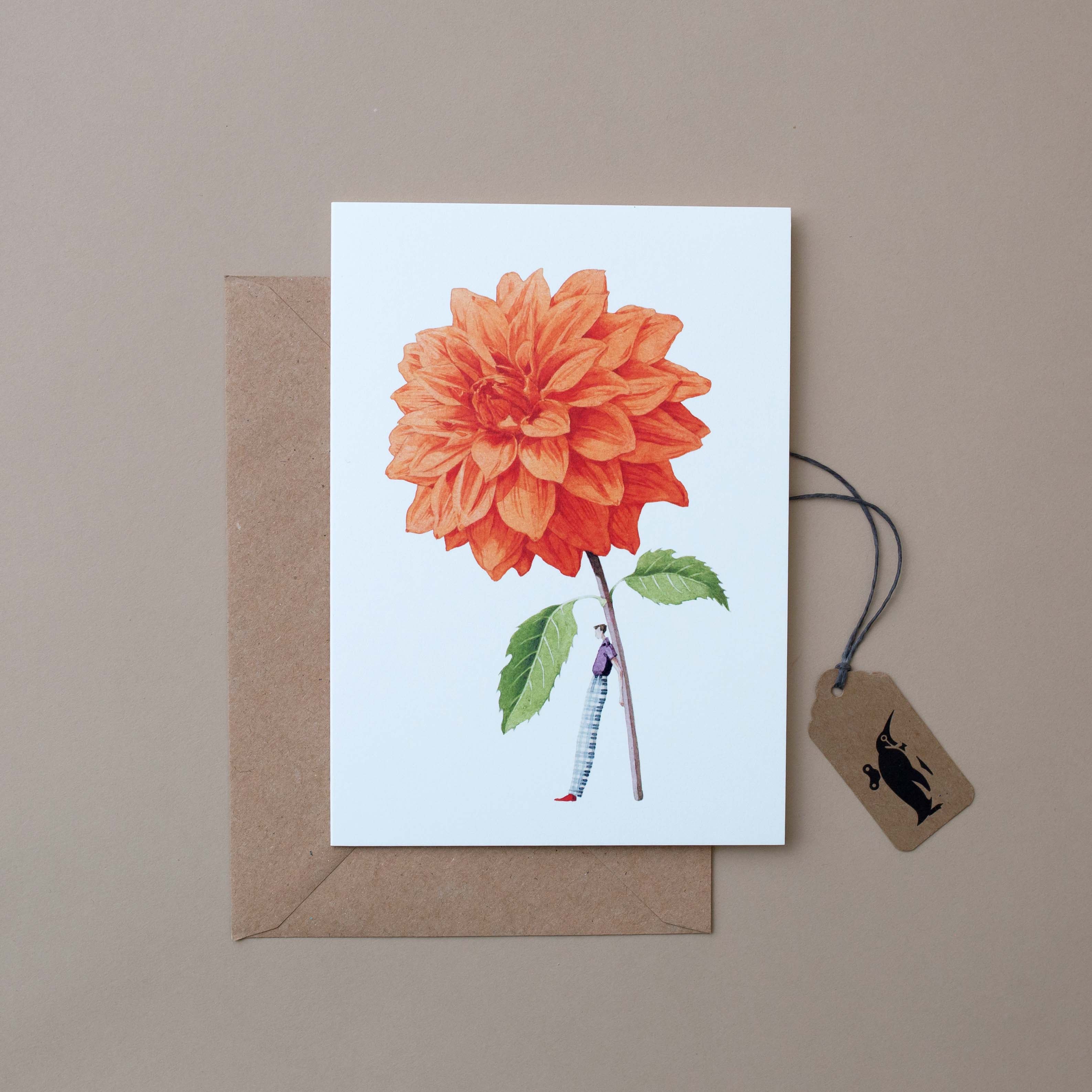 man-holding-oversized-orange-dahlia-on-white-background-and-craft-paper-envelope