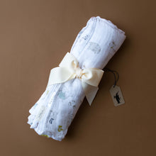 Load image into Gallery viewer, muslin-swaddle-with-illustrated-forest-creatures-on-white-background-rolled-and-tied-with-cream-ribbon