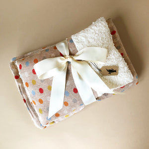 grey-blanket-and-pillow-with-colorful-polka-spots-tied-together-with-white-bow