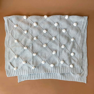 grey-organic-knitted-pom-pom-blanket-with-ivory-poms-unfolded