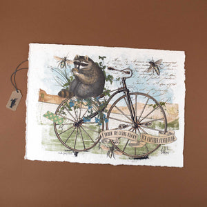 handmade-paper-with-an-illustration-of-a-racoon-sitting-on-a-bicycle-holding-a-nut-in-his-hands