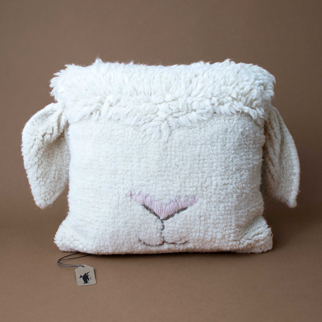white-square-pillow-with-pink-sheep-nose-and-ears-sticking-off-of-it