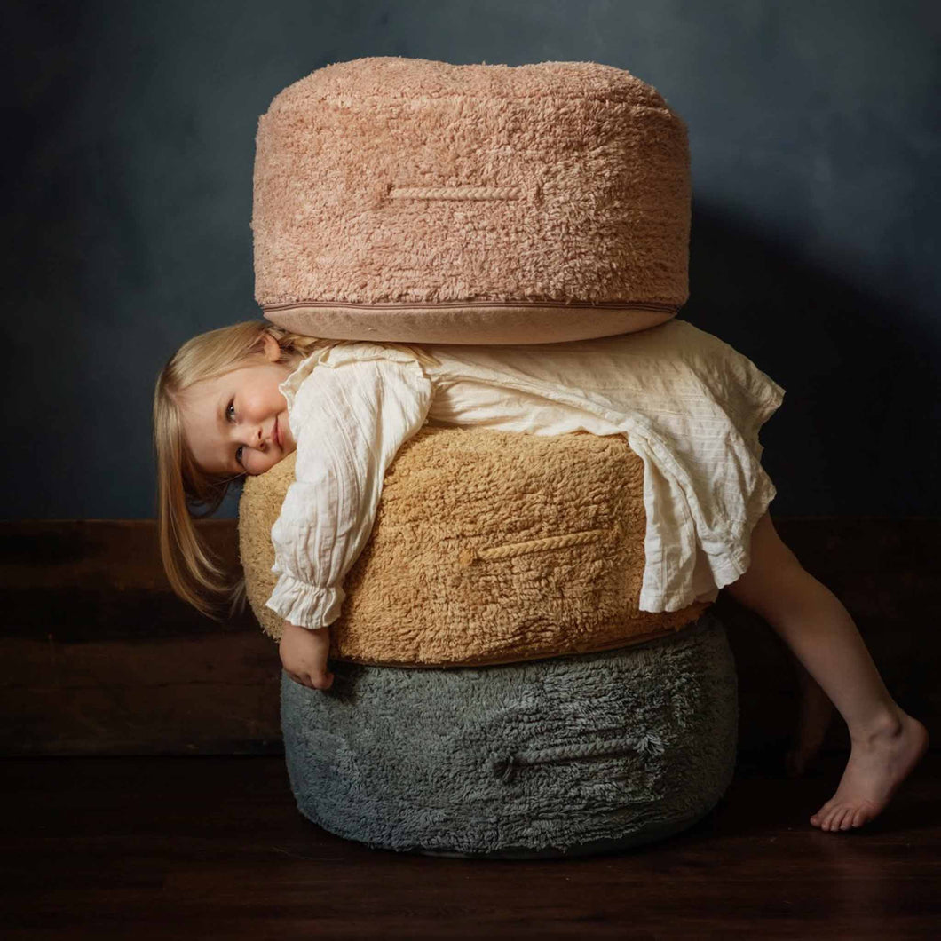 girl-between-stack-of-three-round-poufs-in-rose-honey-and-blue