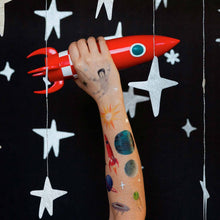 Load image into Gallery viewer, space-themed-tattoos-on-light-skinned-model-holding-red-rocket