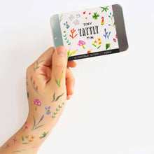 Load image into Gallery viewer, floral-garden-tattoos-on-light-skinned-model-holding-tattoo-tin