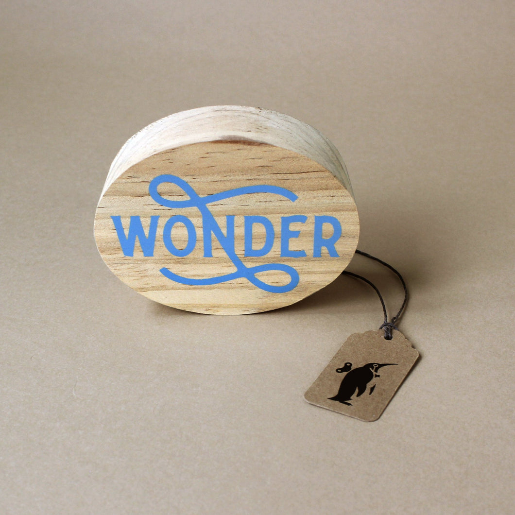 round-wood-block-with-the-word-wonder-printed-in-blue-script