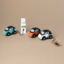 Load image into Gallery viewer, three-small-wooden-cars-standing-next-to-electric-station-getting-fueled