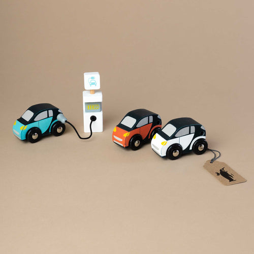 three-small-wooden-cars-standing-next-to-electric-station-getting-fueled