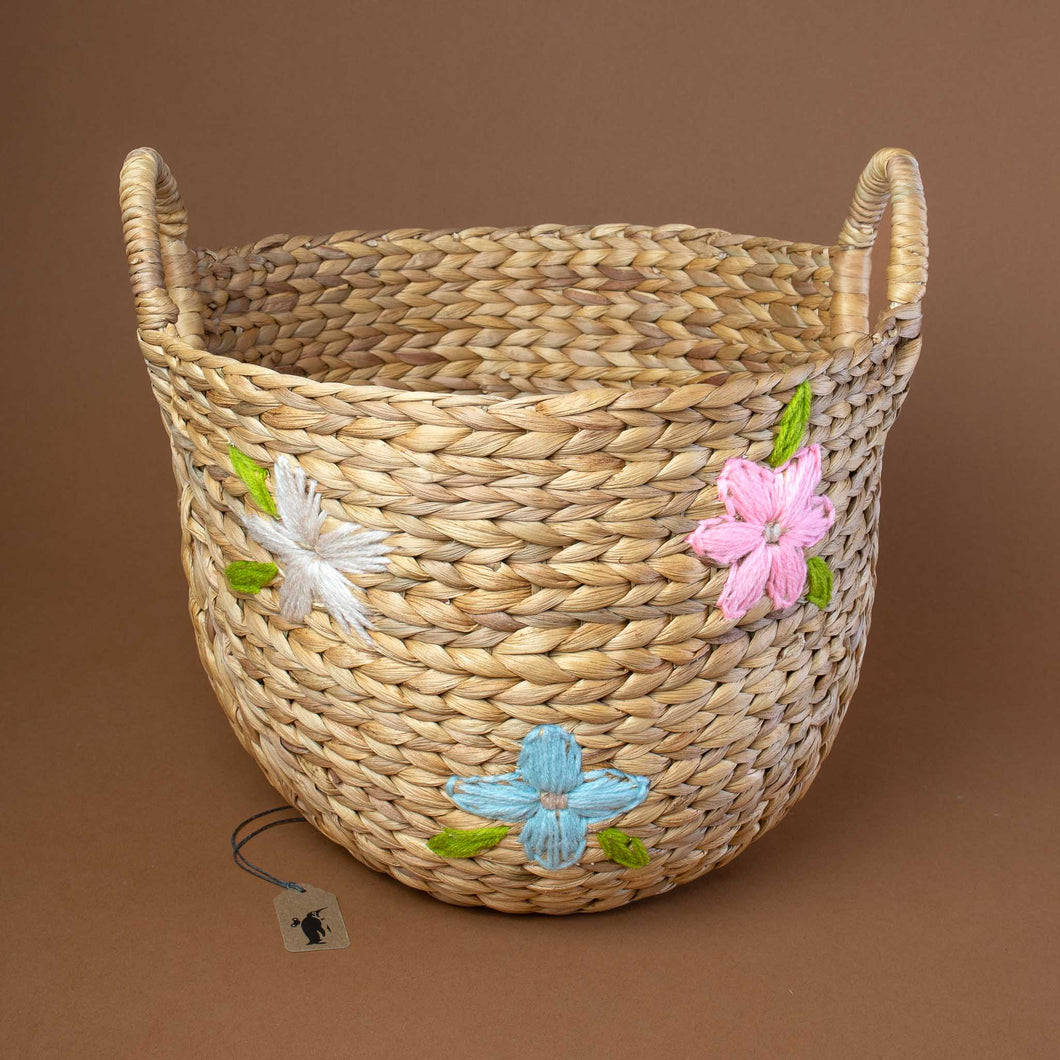 light-brown-woven-round-basket-with-three-floweres-embroidered-in-colors-pink-blue-and-white